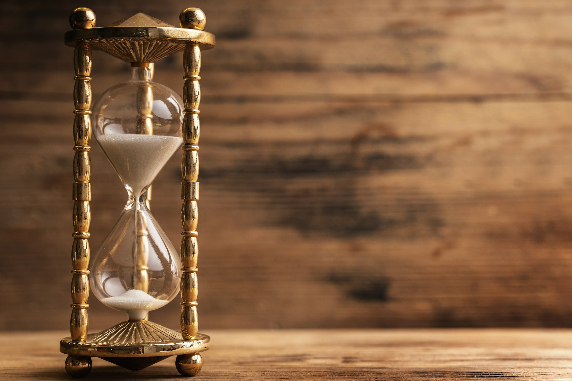 Hourglass on the wooden table with a wooden background